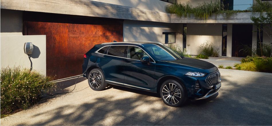 Ein geparkter WEY 05 lädt über eine Wallbox vor einem Wohnhaus.